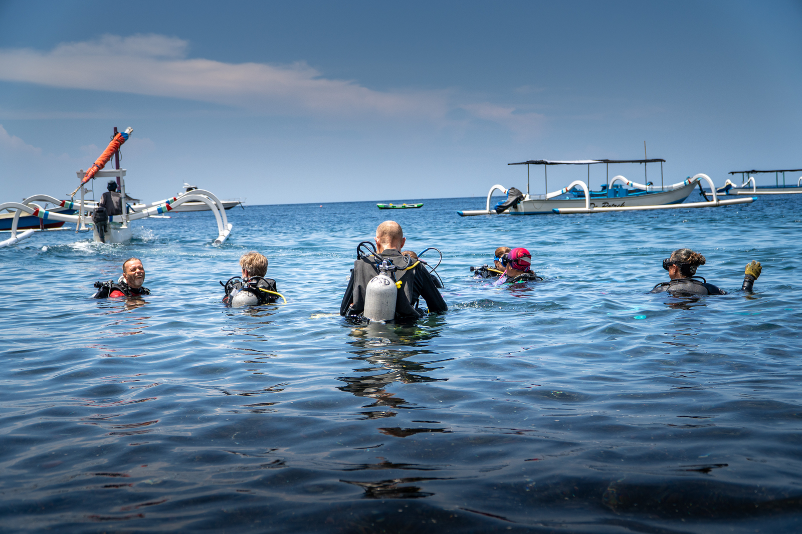 Divers wading into the sea from traditional Balinese boats in Amed
