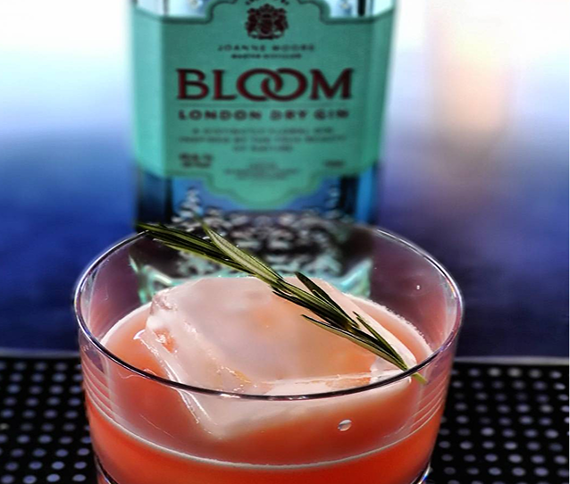 Pink cocktail beside a bottle of gin