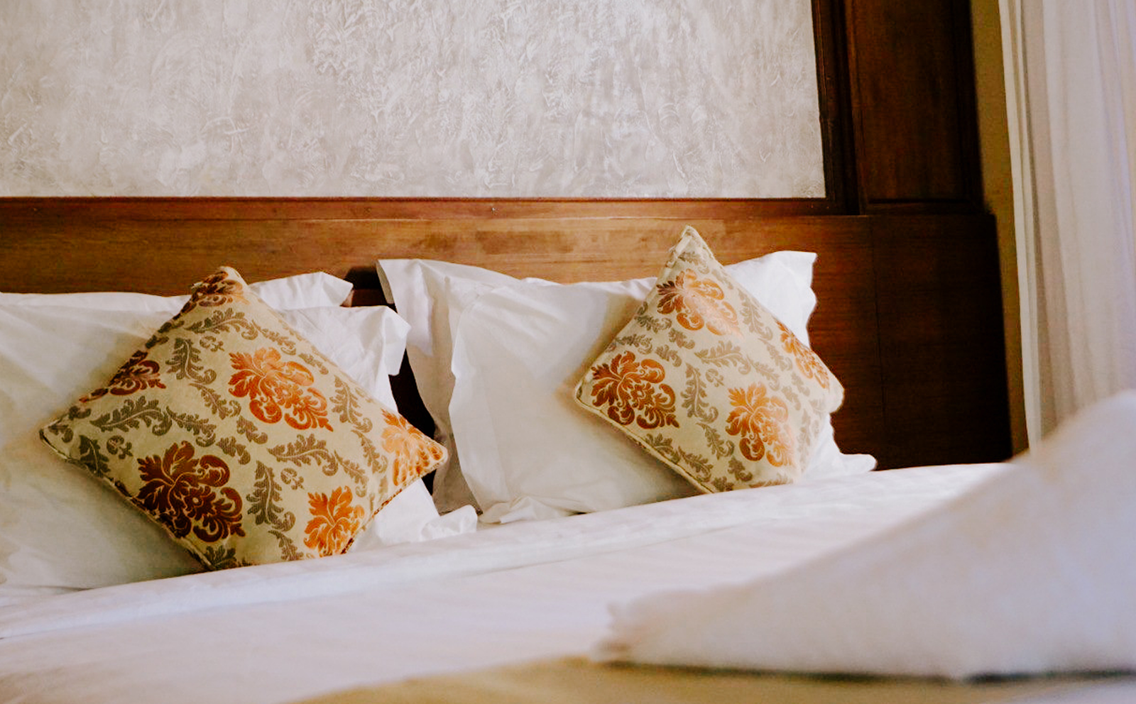 Close-up of a Balinese-carved bed headboard with patterned cushions